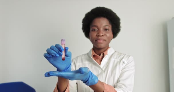Una scienziata africana che fa esami del sangue in laboratorio. Test Covid 19. Il medico virologo alza la mano, mostra la provetta del sangue. Vaccino, cura della malattia — Video Stock