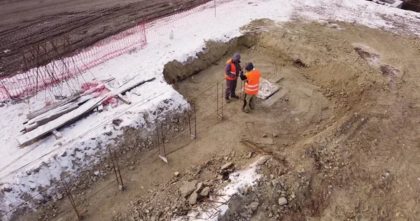 Robotnicy budowlani budują metalową konstrukcję. Pracownicy pracujący na budowie usunęli się z drona. Budowniczowie budują dom. Widok z quadcoptera — Zdjęcie stockowe