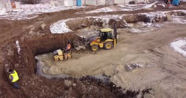 Ağır makinelerin hava görüntüsü, traktör taşıma arazisi, inşaat hazırlığı. Buz pateni pisti zemini sıkıştırır. Bina fiskesi inşaatı başlıyor.