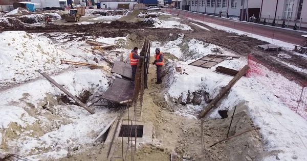 Інженери працюють з металевими конструкціями під час будівництва будинку. Повітряний політ над місцем розробки нових конструкцій. Вид зверху вниз на підрядниках в капелюхах безпеки . — стокове фото