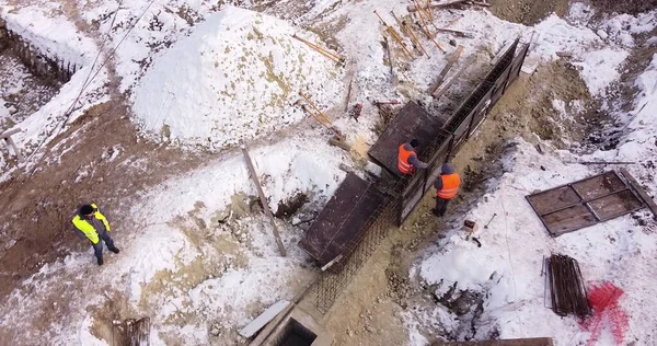 Insinöörit työskentelevät metallirakenteiden kanssa rakentaessaan taloa. Antenni lento yli uusien rakenteiden kehittämisen sivusto. Top Down View at Urakoitsijat Safety Hats. — kuvapankkivalokuva