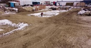 Evin temelini oluşturan beton dökme hazırlığı. İnşaat alanında kürekle çalışan bir işçi. Kış mevsiminde inşaat zor çalışma koşulları, bölgede bir kişi