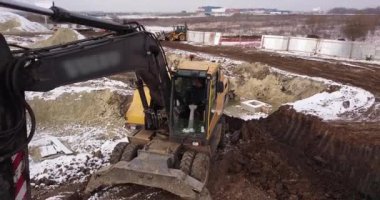 Sürüngen kazıcı inşaat alanında çalışıyor. Şantiyelere kargo taşımak, yüklemek, kazmak ve taşımak için inşaat makineleri. Hava üst görünümü, 4K Video
