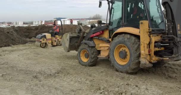 Maquinaria de construcción en el trabajo en la construcción de una casa. Diferentes tipos de tractores y excavadoras preparan el suelo para la construcción de plantas en la zona industrial. Paseos Bulldozer en Sandy Road — Vídeo de stock