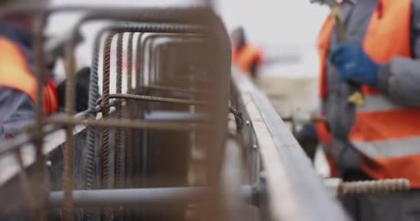 Ingenieurs werken met metalen constructies tijdens het bouwen van een huis. De arbeider maakt de vorm voor het gieten van beton, richt metalen platen. Het vullen van de fundering van het gebouw — Stockvideo