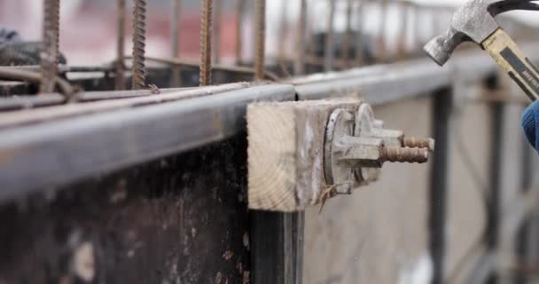 Gli ingegneri lavorano con costruzioni metalliche durante la costruzione di una casa. L'operaio fissa il modulo per versare il calcestruzzo, allinea le tavole metalliche. Riempire le fondamenta dell'edificio. Il martello fissa la forma — Video Stock