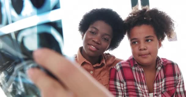 Close-up X-ray of a Mixed Race African American Child. Female Pediatrician Examines Childs X-Ray With Black Mother. Child Girl On A Medical Visit With Mom In Hospital. Child Health Concept — Stock Video