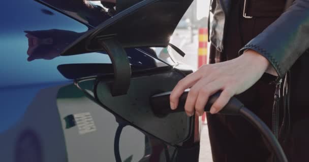 Een elektrische auto opladen. Slow Motion. Een vrouwenhand raakt de stekker van het laadstation aan. Vrouw aansluiten van een voedingskabel in een elektrische auto voor het opladen van een EV-batterij. — Stockvideo