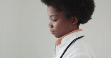 Hastaların boyunlarını muayene eden ve grip sırasında salgı bezlerini inceleyen bir tıp uzmanı. Genç Avrupalı bir kız, Afro-Amerikalı bir kadın doktorda resepsiyonda, beyaz bir tıbbi önlük giyiyor.