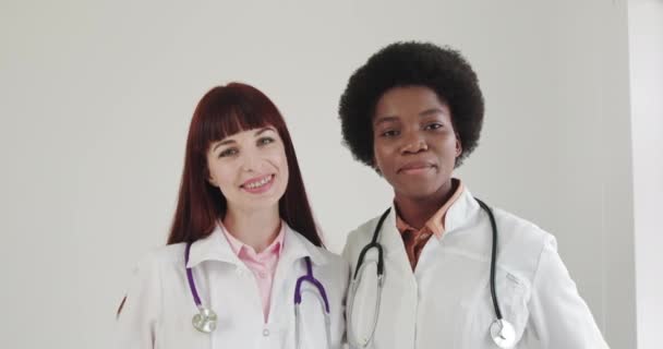 Portret van twee lachende vrouwelijke artsen tevreden met hun werk in het ziekenhuiskantoor. Concept van medische technologie, gezondheidszorg en mensen, ziekenhuis. Artsen van verschillende nationaliteit, Stethoscoop — Stockvideo