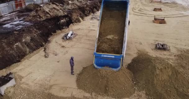 Camión volquete descargando tierra o arena en el sitio de construcción. Camión cargado de tierra y tierra viaja en un complejo de construcción de carreteras — Vídeos de Stock