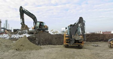 Bir ev inşa etmek için inşaat makineleri çalışıyor. Farklı türde traktör ve kazıcılar, toprağı sanayi bölgesinde fabrika inşaatı için hazırlar. Sandy Yolu 'nda Buldozer Sürüşleri
