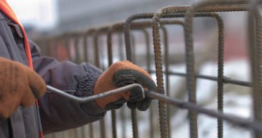 Mühendisler bir ev inşa ederken metal inşaatlarda çalışıyorlar. İnşaatın temelini güçlendirmek için takviye gücü kullanan işçilere yakın durun.