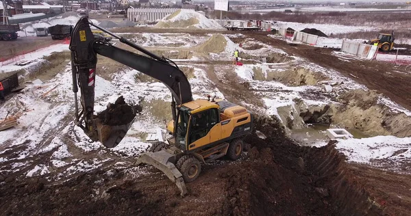 Flug aus der Luft über ein Neubaugebiet mit einem vielfältigen Team von Ingenieuren und Architekten zur Diskussion von Immobilienprojekten. Schwere Maschinen und Bauarbeiter sind im Einsatz. — Stockfoto