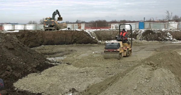 Bodenaushärtung durch schwere Baumaschinen Straßen- und Fabrikbau. Radlader, Planierraupe und Walzenarbeit auf der Baustelle. Maschinen führen Aushubarbeiten durch. Bodenverdichtung — Stockfoto