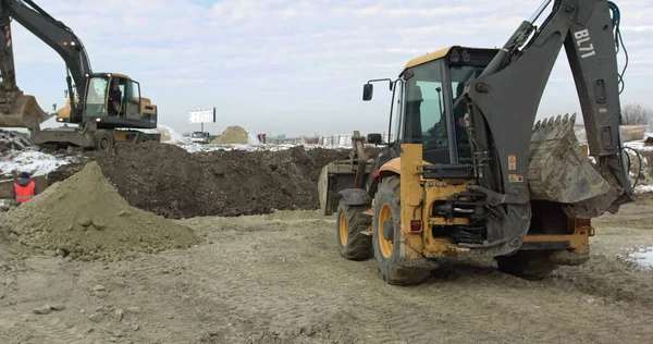 Építőipari gépek dolgoznak egy ház építésén. Különböző típusú traktorok és kotrógépek előkészítik a talajt a növényépítéshez az ipari övezetben. Buldózer Rides a Sandy Road-on — Stock Fotó