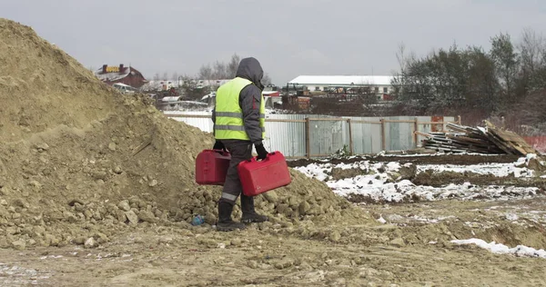 Munkás profi földmérnök Az építkezésen a kezében két piros bőrönd. Teodolit geodéziai optikai műszert alkalmazó munkavállaló a szögek mérésére különböző síkokban — Stock Fotó