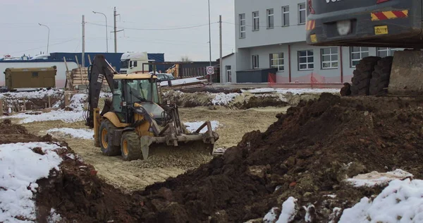 Buldożer pracuje na placu budowy z piaskiem, widok z boku. Nowy Wielki Ciągnik, buldożer na kołach na piaszczystej drodze na placu budowy poziomuje teren pod budowę nieruchomości — Zdjęcie stockowe