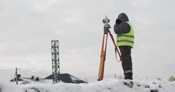 Byggnadsingenjör som övervakar arbetet på byggarbetsplatsen. Professionell ingenjör lantmätare vidtar åtgärder med teodolit. Arbetstagare med hjälp av en teodolit geodetisk optisk anordning på en byggarbetsplats — Stockfoto