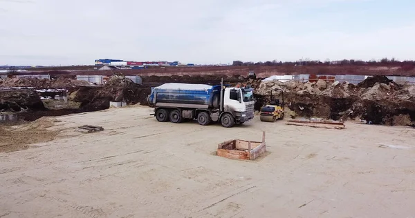 Camión cargado de tierra y tierra viaja en un complejo de construcción de carreteras. Camión volquete descargando tierra o arena en el sitio de construcción — Foto de Stock