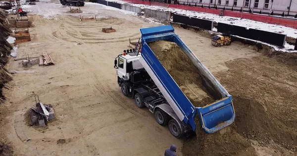 Camión volquete descargando tierra o arena en el sitio de construcción — Foto de Stock