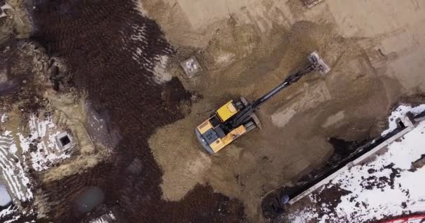 Una excavadora industrial en una sección de carretera abierta carga roca y tierra en un camión volquete muy grande, cargado con mineral. El cubo de la excavadora gotea y carga el mineral. Panorama de las obras de construcción. — Vídeo de stock