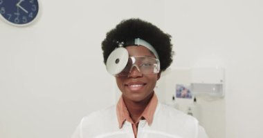 Afrika kökenli Amerikalı Mutlu Güzel Kadın Doktor Klinikte Kameraya Gülümsüyor. Hastanedeki neşeli kadın doktor ya da hemşirenin portresi. Profesyonel Gözlüklü Doktor ENT