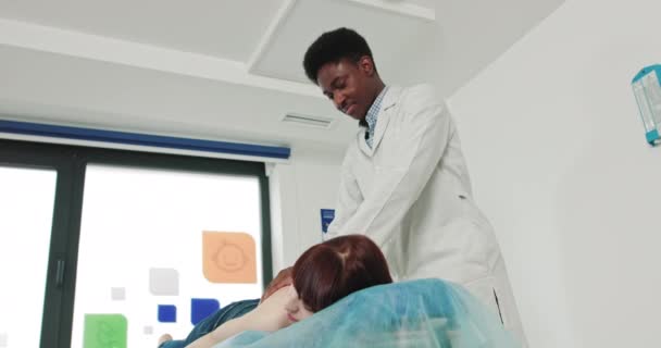 Afrikaanse fysiotherapeut voert massagetherapie, om jonge vrouw om spierkracht te herstellen, in de Moderne Revalidatie Kliniek. Terug Gezondheid. Kinesiologie. Herstelbehandeling. Revalidatie. — Stockvideo