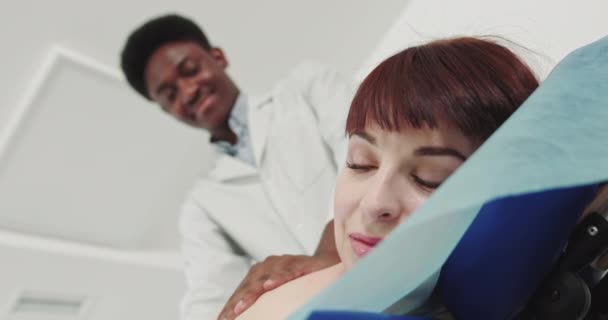 Ontspannen vrouw krijgt schoudermassage. Wellness, Genezing en Ontspanning Concept. Afro-Amerikaanse fysiotherapeut voert therapeutische massage therapie aan een jonge vrouw om spierkracht te herstellen — Stockvideo