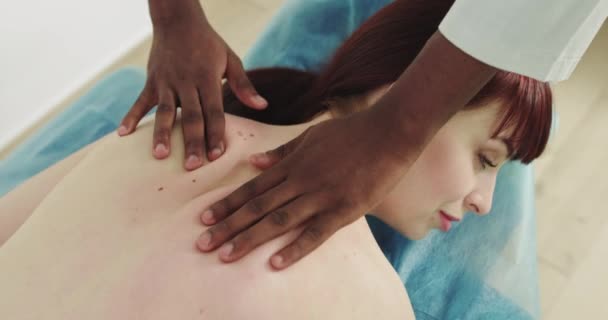 男治疗师对躺在温泉柜沙发上的女病人进行按摩。美容院女病人恢复按摩程序。肩部及颈部按摩. — 图库视频影像