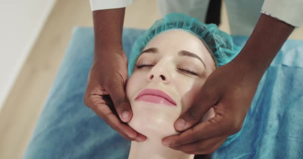 Femeia care primește un masaj facial. Fizioterapeutul efectuează terapia terapeutică de masaj la o tânără femeie pentru a restabili puterea musculară în clinica modernă de reabilitare. Body Care Concept — Videoclip de stoc