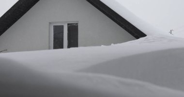 Kışın, kar taneleri ve Noel mevsiminde dondurucu sıcaklıklarda donmuş bir evin çatısı. Beyaz bulutlu karla kaplı çatı ve bokeh - Yavaş Hareketi Kapat