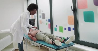 Kameraya Bakan Çekici Afro-Amerikan Kadın Doktor Portresi. Meslek, Hastane, Sağlık Hizmetleri. Doktor kardiyolog hastayı EKG makinesine bağlıyor. Kardiyograma Hazırlanıyor