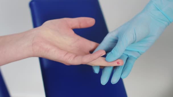 Le médecin prélève un échantillon de sang du doigt du patient pour le tester à la COVID-19. Les mains du médecin dans les gants de protection piquent doigt de l'homme avec une aiguille pour prendre l'analyse au coronavirus pendant la pandémie. Gros plan — Video