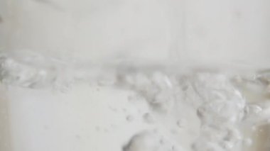 Kaynayan suyu şeffaf bir kabın içinde ya da cam bir çaydanlıkta ya da tencerede, kaynayan suyun güçlü kaynayan sıvısında yakın görüntüsü. Saf su bardağa döküldü. Yakın çekim.