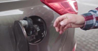 Benzin ikmali yapan bir adamın benzin istasyonundaki bir arabada çekilmiş yakın çekimi. Full Diesel Tank, Yakıt Yakıtı 'nın Sonu. Adam makineli tüfeğini makineden çıkarır ve tankın kapağını kapatır çevirisi: dizel.