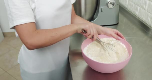 Cuoco, mescolando la farina in una ciotola rosa con una frusta, mentre in piedi in dolci leggeri interni. Preparazione per fare i maccheroni nel laboratorio di panetteria. Impastare la farina a mano — Video Stock