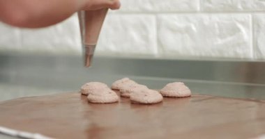 Şef makaron tatlısı hazırlamak için zemin hazırlıyor. Makaron tatlısı pişirmek için metal tepside bulunan boru torbasından çıkan kas kreminin yakın çekimi..