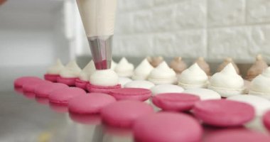 Fırın, şekerleme dükkanı, insan konsepti. Pişirme, Yemek ve Pişirme Konsepti. Şekerleme çantalı aşçı, beyaz makaron kabuklarıyla krema sıkıyor..