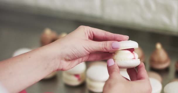 Die Verbindung der beiden mit Marmelade und Ganache verzierten Schalen von Macarons. Typischer Prozess der Verbindung von zwei Makronenhälften mit Sahnefüllung in den Händen des Küchenchefs. Nahaufnahme. — Stockvideo