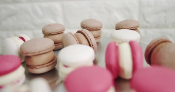 Close-up van kleurrijke witte, rode en karamel chocolade macarons dessert, gevuld met smakelijke ganache, op de tafel in de lichte keuken of zoetwaren winkel. Panorama meerkleurige Franse amandelmakaken — Stockvideo