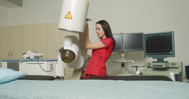 Ritratto di giovane donna attraente medico, in piedi vicino al moderno litotripter ultrasonico mentre si prepara per la terapia extracorporea d'onda d'urto nel moderno centro urologico. Impostazioni litotripter ad ultrasuoni — Video Stock