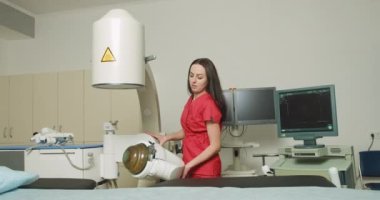 Kendine güvenen, kırmızı üniforma giyen, modern klinikte ultrasonik lithotripter makinesiyle çalışan beyaz kadın bir doktor portresi. Böbrek taşı tedavi konsepti