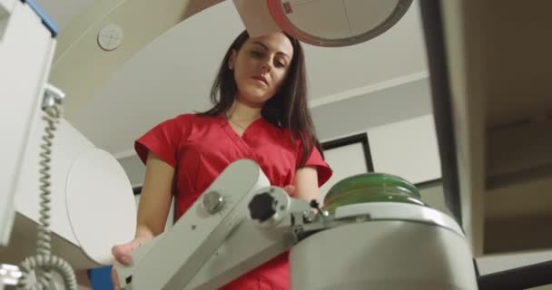 Zblízka dolní pohled na vysoce kvalifikované ženské lékaře v červené uniformě, stojící v blízkosti moderního stroje pro neinvazivní extrakorporální rázovou vlnu litotrypse rozbít ledviny nebo močovodu kameny — Stock video
