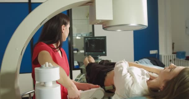 Extracorporeal shock wave therapy. Kidney stone treatment. Front view of woman doctor looking at the digital screen of the lithotriptor to determine stones position of woman patient — Stock Video