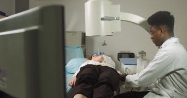 Extracorporeal şok dalga terapisi. Böbrek taşı tedavisi. Afrikalı erkek doktor, kadın hastanın taş pozisyonunu belirlemek için lithotriptorun dijital ekranına bakıyor.