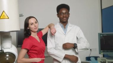 İki gülümseyen profesyonel doktorun, Afrikalı erkek ve beyaz kadının, ultrason ve lithotripter makinelerinin önünde duran portresi. Güvenlik ihlalsiz taş tedavisi