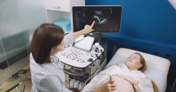 Di Rumah Sakit, Obstetrician Uses Transducer for Ultrasound, Sonogram Screening, Scanning Belly of the Pregnant Woman. Dokter perempuan menunjuk pada layar mesin USG. — Stok Video