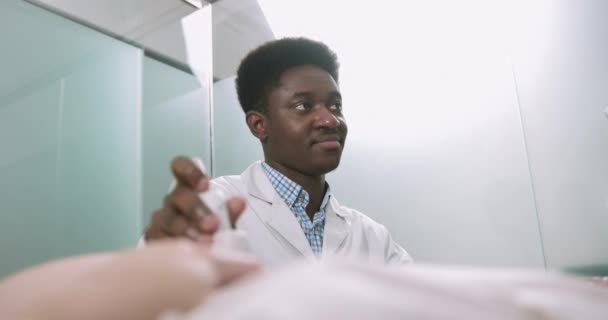 Vedere laterală a unui medic afro-american zâmbitor care face scanări cu ultrasunete pentru o femeie gravidă de nerecunoscut în spital. Diagnosticul cu ultrasunete al sarcinii — Videoclip de stoc