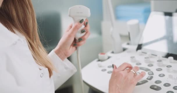 Zbliżenie przycięty portret kobiety profesjonalny lekarz USG USG przy użyciu nowoczesnej maszyny w pracy, trzymając w ręku przetwornik ultradźwiękowy. Koncepcja urządzeń ultradźwiękowych — Wideo stockowe